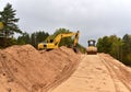 Excavator and Vibro Roller Soil Compactor at road construction and bridge projects in forest area. Heavy machinery for road work.