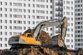 Excavator work on the ground on background of multi storey houses.
