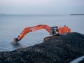 Excavator work at night. Overtime work. The work of construction equipment on the seashore. Batumi. Fortified shores. at sunset.