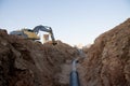 Excavator at work trenching at a construction site. Trench for laying external sewer pipes. Sewage drainage system for a multi-