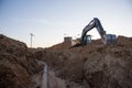 Excavator at work trenching at a construction site. Trench for laying external sewer pipes. Sewage drainage system for a multi- Royalty Free Stock Photo