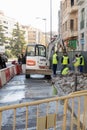 Excavator and workers repairing a sidewalk in the city center due to a broken water pipe.