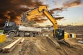 Excavator working on construction site with dramatic clouds on sky Royalty Free Stock Photo
