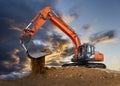 Excavator working on construction site with dramatic clouds on sky Royalty Free Stock Photo