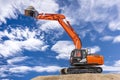 Excavator working on construction site with dramatic clouds on sky Royalty Free Stock Photo
