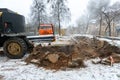 The excavator is working on the construction site to replace the pipeline in winter. Digging holes for laying new pipes for