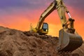 Excavator working on earthmoving at open pit mining on amazing sunset background. Backhoe digs sand and gravel in quarry. Heavy Royalty Free Stock Photo