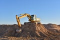 Excavator working on earthmoving at open pit mining. Yellow Backhoe digs sand and gravel in quarry. Heavy Construction Equipment Royalty Free Stock Photo