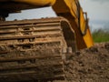 Excavator working in the field, Dirty tracks, Arm digging hole in the ground, Selective focus, Heavy machinery in action. Building