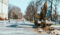 Excavator is working at the road construction. Excavator in the city. Wheeled tractor, heavy machinery working.