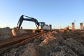 Excavators during earthworks at construction site. Backhoe the digging pit for construct building foundation. Paving out sewer