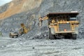 Excavators pour nepheline ore into dump trucks of Caterpillar in a career