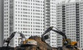 Excavators work on the ground on background of multi storey houses.