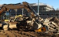 Excavators at work among rubble and dirt. Building under complete refurbishment on background