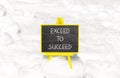 Exceed to succeed symbol. Concept words Exceed to succeed on beautiful black chalk blackboard. Beautiful white snow background.