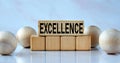 EXCELLENCE - word on wooden cubes on a light background with balls Royalty Free Stock Photo