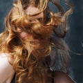 Excellent curly hair. Happy beautiful redheaded girl. Studio portrait on textured background. Flying long hair Royalty Free Stock Photo