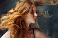 Excellent curly hair. Happy beautiful redheaded girl. Studio portrait on textured background. Flying long hair Royalty Free Stock Photo