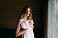 Excellent girl standing at the window and holding a white dress