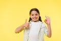 Excellent quality. Kid girl shows thumb up and ok gesture yellow background. Child highly recommend excellent quality