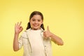 Excellent quality. Kid girl shows thumb up and ok gesture yellow background. Child highly recommend excellent quality