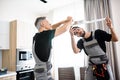 We are excellent. Two electricians, workers in uniform installing electric lamp, light inside apartment in the kitchen