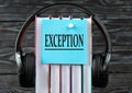 EXCEPTION - word on a blue piece of paper on the background of a stack of books and headphones. Freedom of Information Act concept