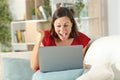 Excited adult lady celebrates news on laptop at home