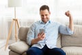 Excited adult man feeling ecstatic holding phone