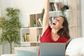 Excited adult woman celebrates news on laptop at home
