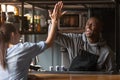 Excited African American barista giving high five with woman at work Royalty Free Stock Photo