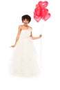 African american bride holding heart-shaped balloons while standing in wedding dress isolated on white Royalty Free Stock Photo