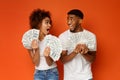 Excited african american couple holding bunch of money banknotes