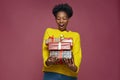 Excited african american girl in yellow sweater hold present boxes. Amazed black young woman looking on gifts in hands Royalty Free Stock Photo