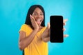 Excited African American Lady Showing Phone Screen On Blue Background