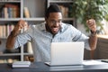 Excited African American man reading good news, using laptop Royalty Free Stock Photo