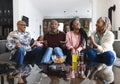 Excited african american parents, son, daughter and grandparents watching sport on tv, slow motion