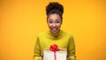 Excited African-American woman holding gift box, pleasant birthday surprise
