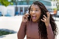 Excited african american young adult woman listening to boyfriend at phone Royalty Free Stock Photo