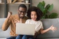 Excited african father and kid girl winners looking at laptop