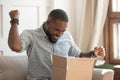 Excited african man customer receive open parcel box at home