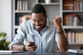 Excited African man looking at smartphone screen read unbelievable message