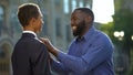 Excited african man feeling proud of young son in prom suit, college graduation