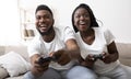 Excited afro couple playing video games at home together using joysticks Royalty Free Stock Photo