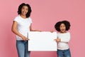 Excited Afro mother and daughter holding and pointing at white placard