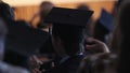 Excited alumnus in mortarboard applauding rector's speech at graduation ceremony