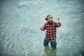 Excited amazed fisher man in water catching trout fish, top view. Young man fishing. Fisherman with rod, spinning reel