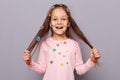 Excited amazed smiling girl covered colorful kid's stickers standing isolated over gray background pulling her hair aside Royalty Free Stock Photo