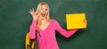 Excited amazed teacher. Student girl holding empty faper for product. Portrait of smiling female teacher near blackboard