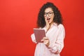 Excited amazed young beautiful woman with tablet pc. Happy girl in white shirt using tablet computer, isolated on red background Royalty Free Stock Photo